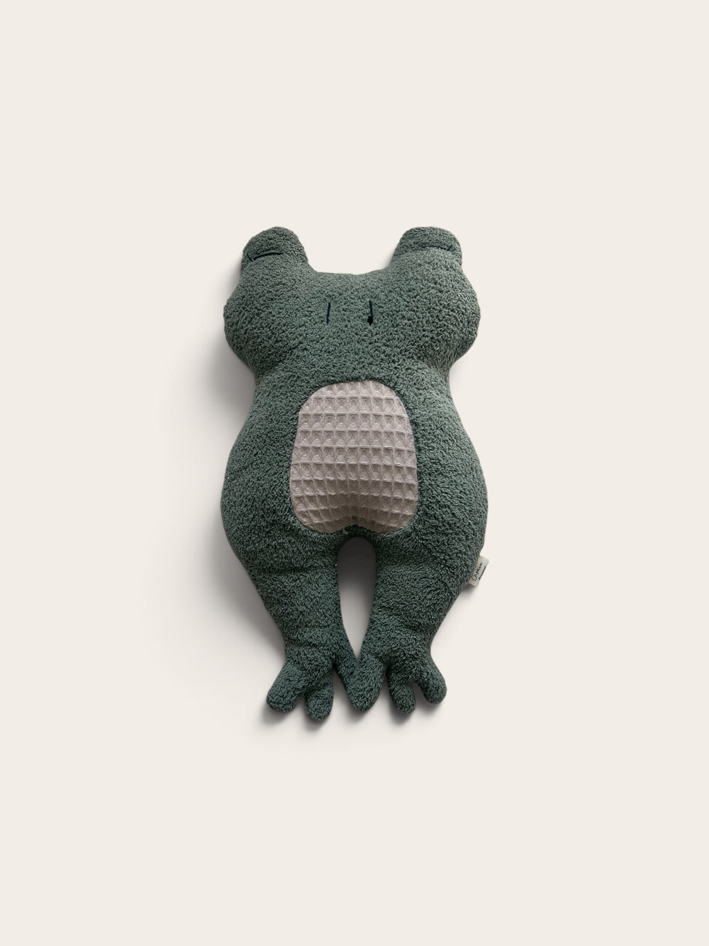 A dark green plush frog toy with a textured light beige belly, photographed against a solid off-white background.