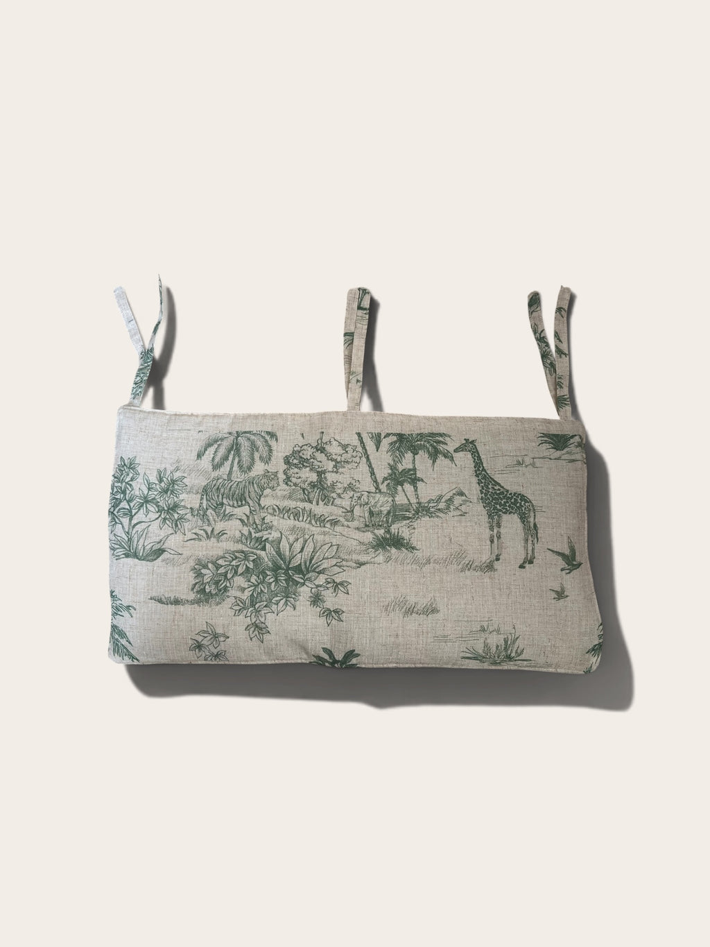 A cot organiser with a green safari toile de Jouy print on a light beige linen background, featuring three adjustable attachment straps and a soft drop shadow on a light beige background.