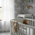 Beige muslin star baby comforter draped over crib as a soft newborn security blanket
