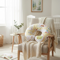 Floral nursing pillow on chair in neutral nursery for breastfeeding and baby support