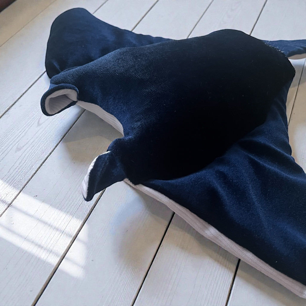 Velvet manta ray plush toy close up on wooden floor soft ocean stuffed animal texture detail