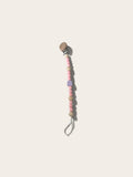 A wooden pacifier clip with pastel pink and beige beads, a small lavender striped accent bead, and a natural wood teething tab on a light cream background.